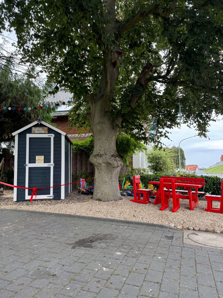 Die Bücher-Kajüte (kleines Holz-Gartenhaus) mit roter Absperr-Schleife